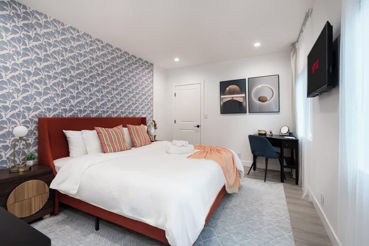 Ein modernes Schlafzimmer mit einem großen Bett, einem Schreibtisch und einem Fernseher.