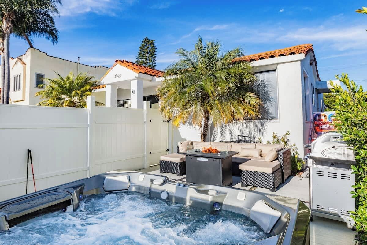 Ein Whirlpool mit Terrassenbereich, Gartenmöbeln und einem Grill.
