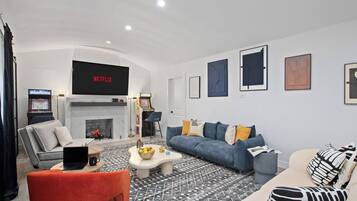 Een moderne woonkamer met een open haard, een bank, een salontafel en een televisie waarop 'NETFLIX' staat.