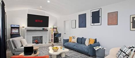 A modern living room with a fireplace, a sofa, a coffee table, and a television displaying 'NETFLIX'.