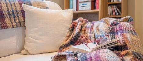 Um quarto acolhedor com uma cama, um cobertor colorido, um travesseiro e uma estante de livros com livros e um rádio.