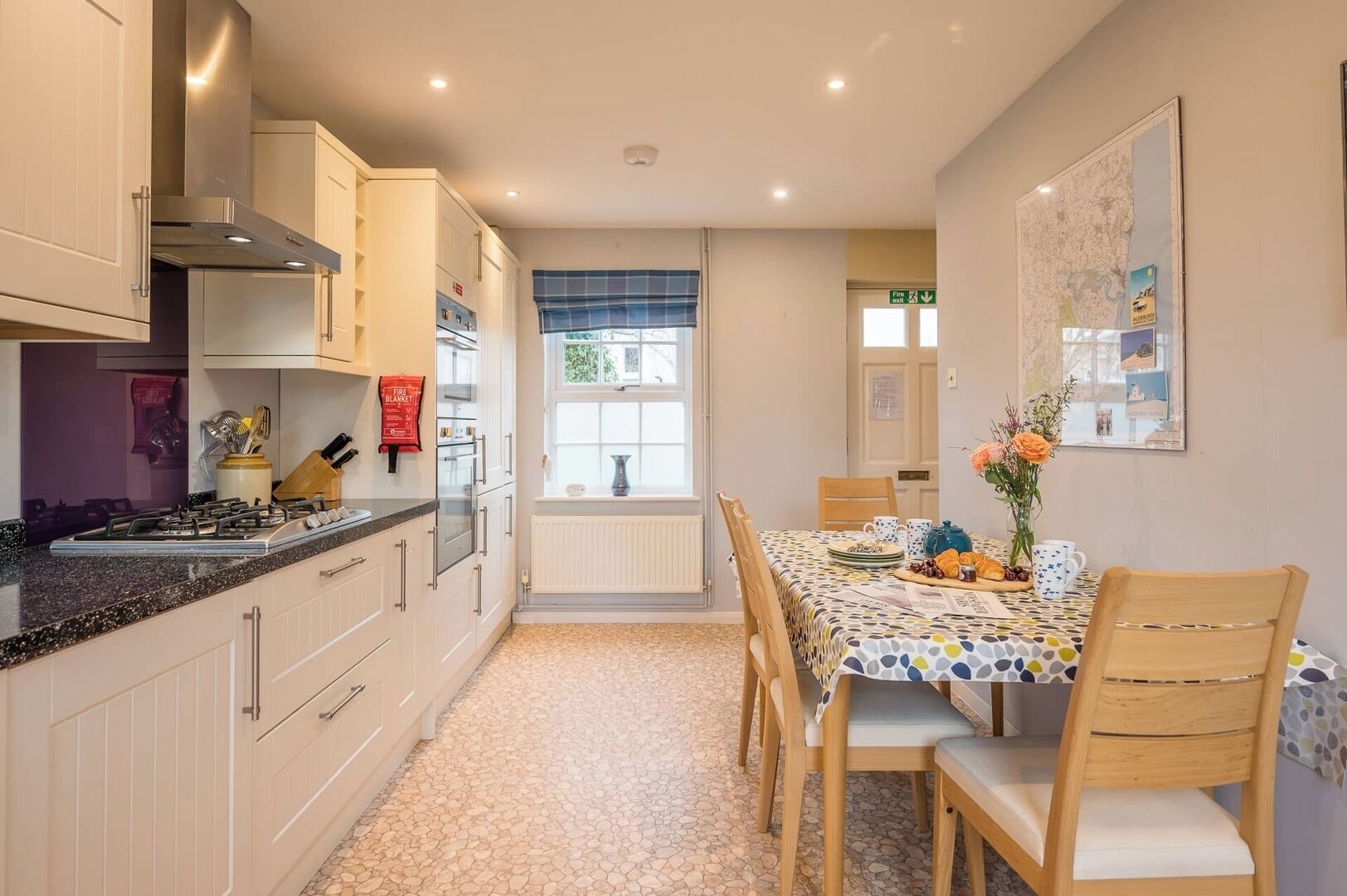 A kitchen with white cabinets, a gas stove, and a dining area with a table set for two.
