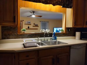A kitchen with wooden cabinets, a double sink, and a ceiling fan.
