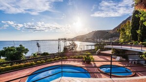 A pool area with two pools, a view of the sea, and a mountainous landscape. - TámuTaormina | Luxury Sea & Etna Views Duplex (Taormina)