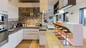 A modern kitchen with a patterned backsplash, a built-in oven, and a bar area with stools. - TámuTaormina | Luxury Sea & Etna Views Duplex (Taormina)