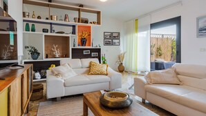 A living room with a white sofa, a wooden coffee table, and a bookshelf filled with decorative items. - TámuTaormina | Luxury Sea & Etna Views Duplex (Taormina)
