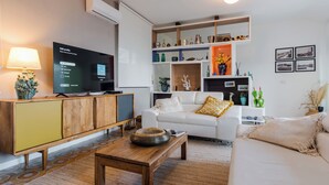 A living room with a TV, a wooden cabinet, a white sofa, and a coffee table. - TámuTaormina | Luxury Sea & Etna Views Duplex (Taormina)
