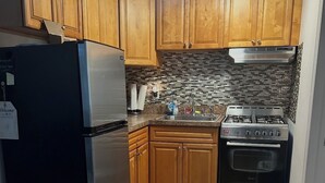 Uma cozinha com armários de madeira, geladeira de aço inoxidável, fogão a gás e painel de azulejos.