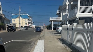 Uma rua com edifícios, calçada e carros estacionados.