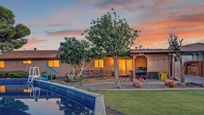 Ein Wohnhaus mit Swimmingpool, Baum und Garage.