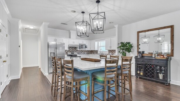 A modern kitchen with a central island, bar stools, and pendant lighting. - Coastal Clubhouse | Hot Tub, Game Room & Pet-Friendly Vacation Home (Saint Simons Island)