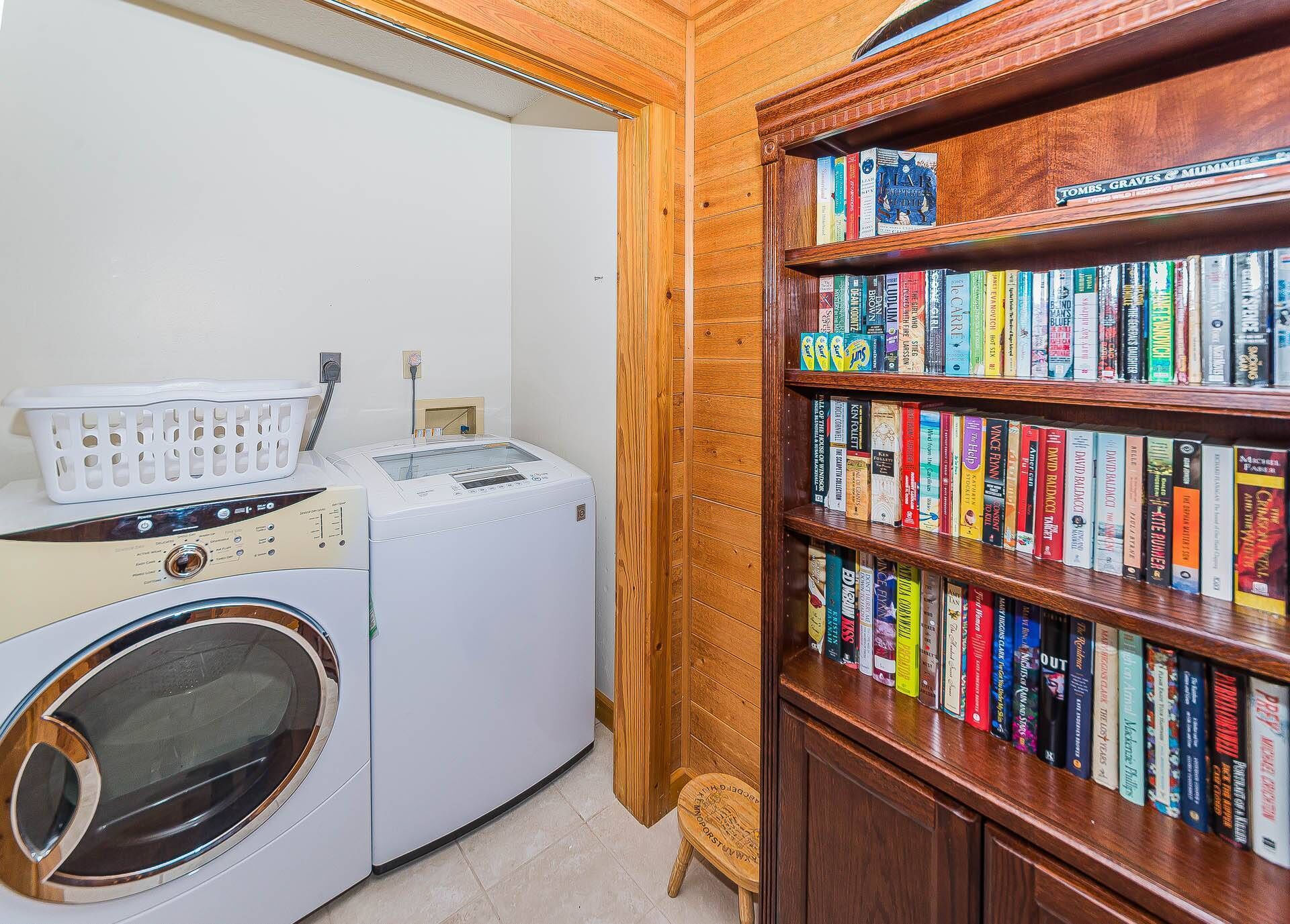 Un espace buanderie comprenant un lave-linge, un sèche-linge et une bibliothèque remplie de livres.