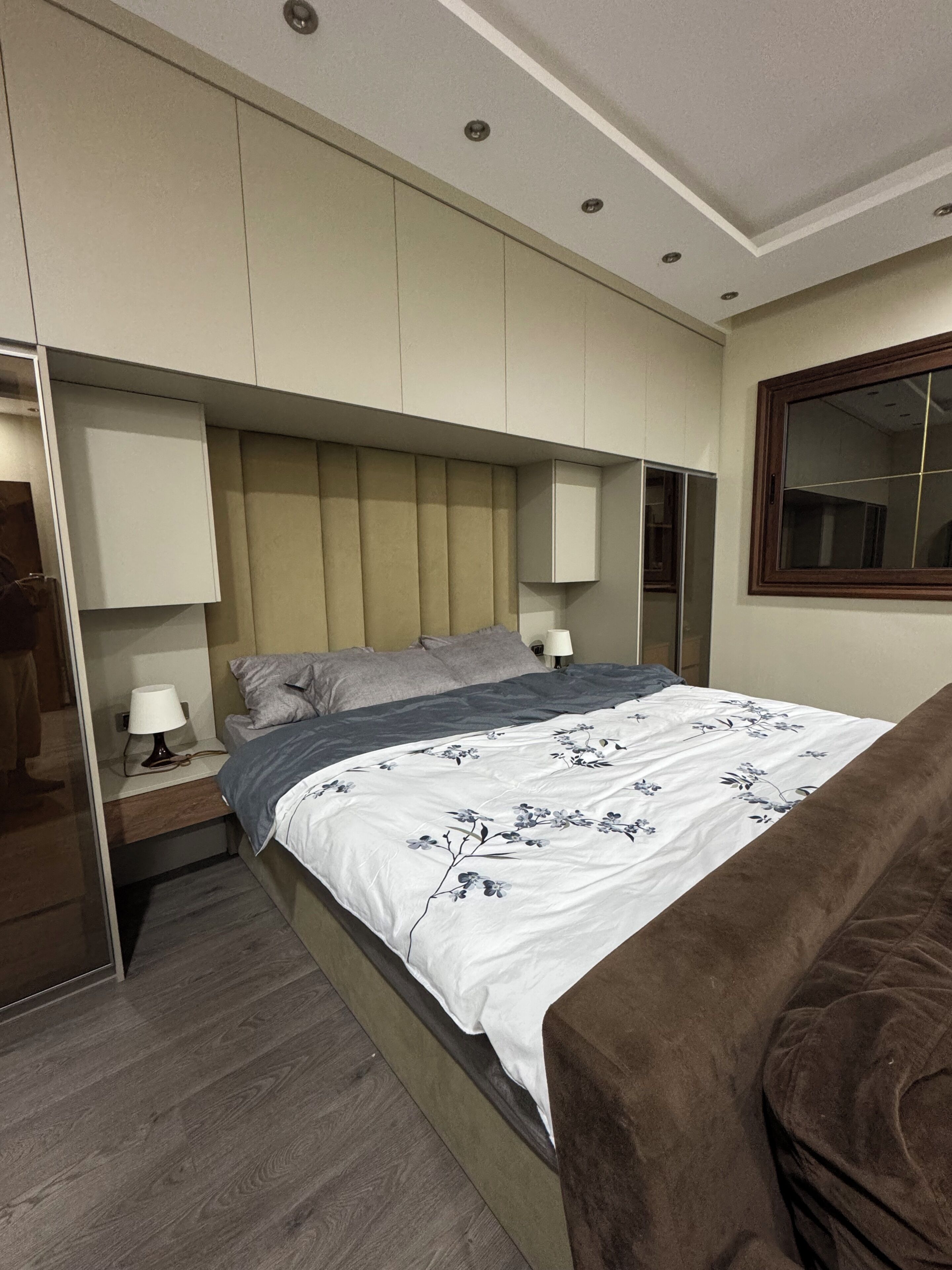 A modern bedroom with a bed, bedside tables, and a wardrobe.