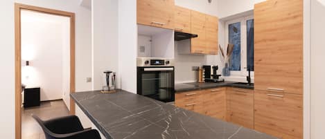 Una cocina moderna con encimera de mármol, armarios de madera y horno empotrado.