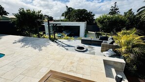 Ein Garten mit Swimmingpool, Sitzgelegenheiten im Freien und einer Pergola.