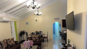 Una sala de estar con sofá, mesa de centro, televisor y un comedor con sillas y una mesa.