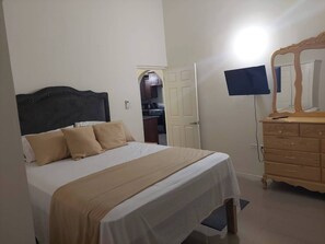A bedroom with a bed, a dresser, a mirror, and a television. - Serenity Vacation Villa (Ocho Rios)