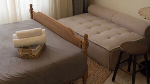A bedroom with a bed, a sofa, a chair, and a small table. - balcony  Studio (Thành phố Hồ Chí Minh)