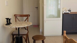 A compact room with a bed, a small round table with two chairs, a cabinet, and a door leading to another room. - balcony  Studio (Thành phố Hồ Chí Minh)