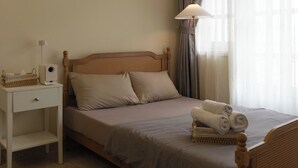 A single bed with a wooden headboard, a bedside table with a lamp, and a window with curtains. - balcony  Studio (Thành phố Hồ Chí Minh)