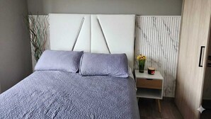 Un dormitorio con cama, mesita de noche y una obra de arte en la pared.