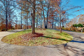 A park with a central grassy area, trees, and a paved path.