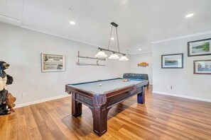 Una mesa de billar en una habitación con suelo de madera y paredes blancas.