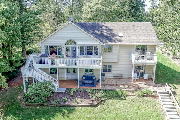 A two-story house with a covered porch, a deck, and a landscaped yard.