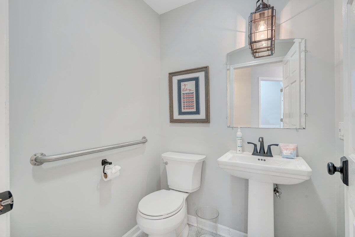 A bathroom with a toilet, sink, and a framed picture on the wall.