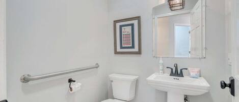 A bathroom with a toilet, sink, and a framed picture on the wall.