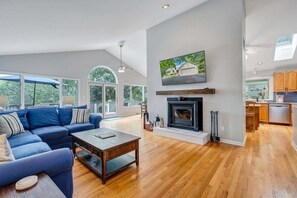 Un salón amplio con chimenea, un sofá grande y un televisor montado encima.