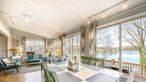 A spacious dining area with a large table, chairs, and a view of a lake. - Cottage at the Lake - Waterfront lake-view home with dock, fireplace, pool table, kayaks, & firepit (Moneta)