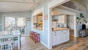 A spacious kitchen with white cabinets, a central island, and a dining area with a table and chairs. - Cottage at the Lake - Waterfront lake-view home with dock, fireplace, pool table, kayaks, & firepit (Moneta)