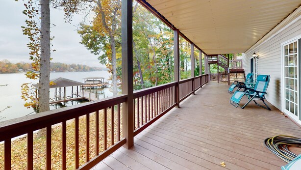 Portico coperto con vista su un lago, terrazza in legno e area salotto esterna.