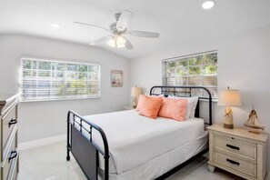 A bedroom with a bed, bedside tables, a ceiling fan, and windows with blinds. - NEW! Heron Lagoon Hideaway: Canal Front, Pool, Dog (Sarasota)