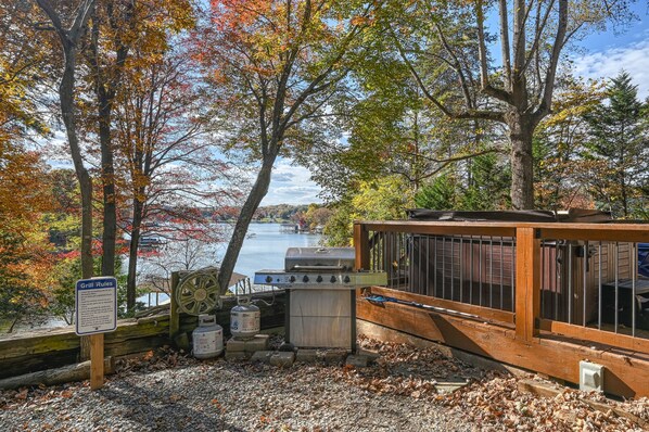 Un chalet au bord du lac, doté d’un espace barbecue, entouré d’un feuillage automnal et offrant une vue sur le lac.