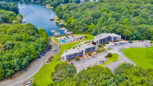 An aerial view of a hotel with a swimming pool, parking area, and boats docked by a lake. - Sunset Landing - Waterfront condo with lake-view deck, tennis court & pool (Moneta)