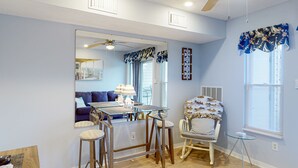 A dining area with a glass table, wooden chairs, and a ceiling fan. - Sunset Landing - Waterfront condo with lake-view deck, tennis court & pool (Moneta)
