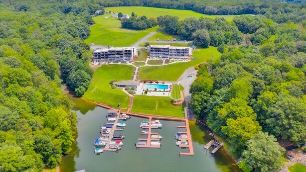 An aerial view of a resort with multiple buildings, a swimming pool, and a marina with boats. - Sunset Landing - Waterfront condo with lake-view deck, tennis court & pool (Moneta)