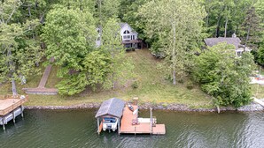 Uma casa com um cais que se estende por um lago, rodeada por árvores.
