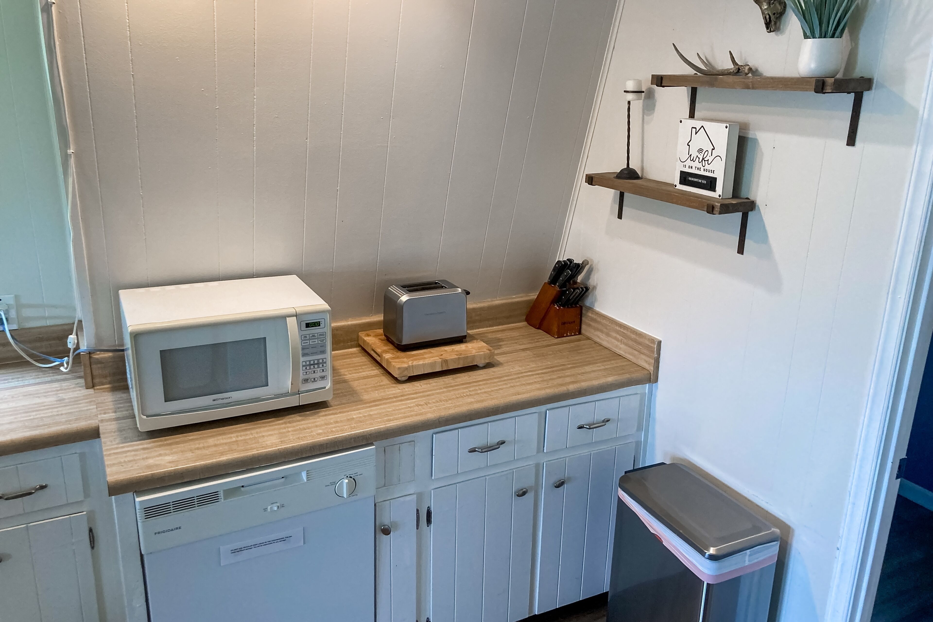 A kitchen with a microwave, toaster, and knife block on the counter.