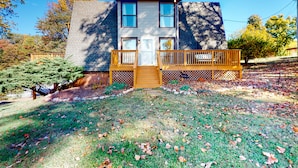 A two-story house with a front deck, a wooden door, and a small porch area. - Dock Sun Point - Lakefront home for easy boating, fishing, private dock & AC/Wifi, Dogs ok! (Huddleston)