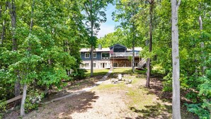 A house surrounded by trees with a pathway leading to the entrance. - The Main House - Lakefront home with private hot tub & balcony (Huddleston)
