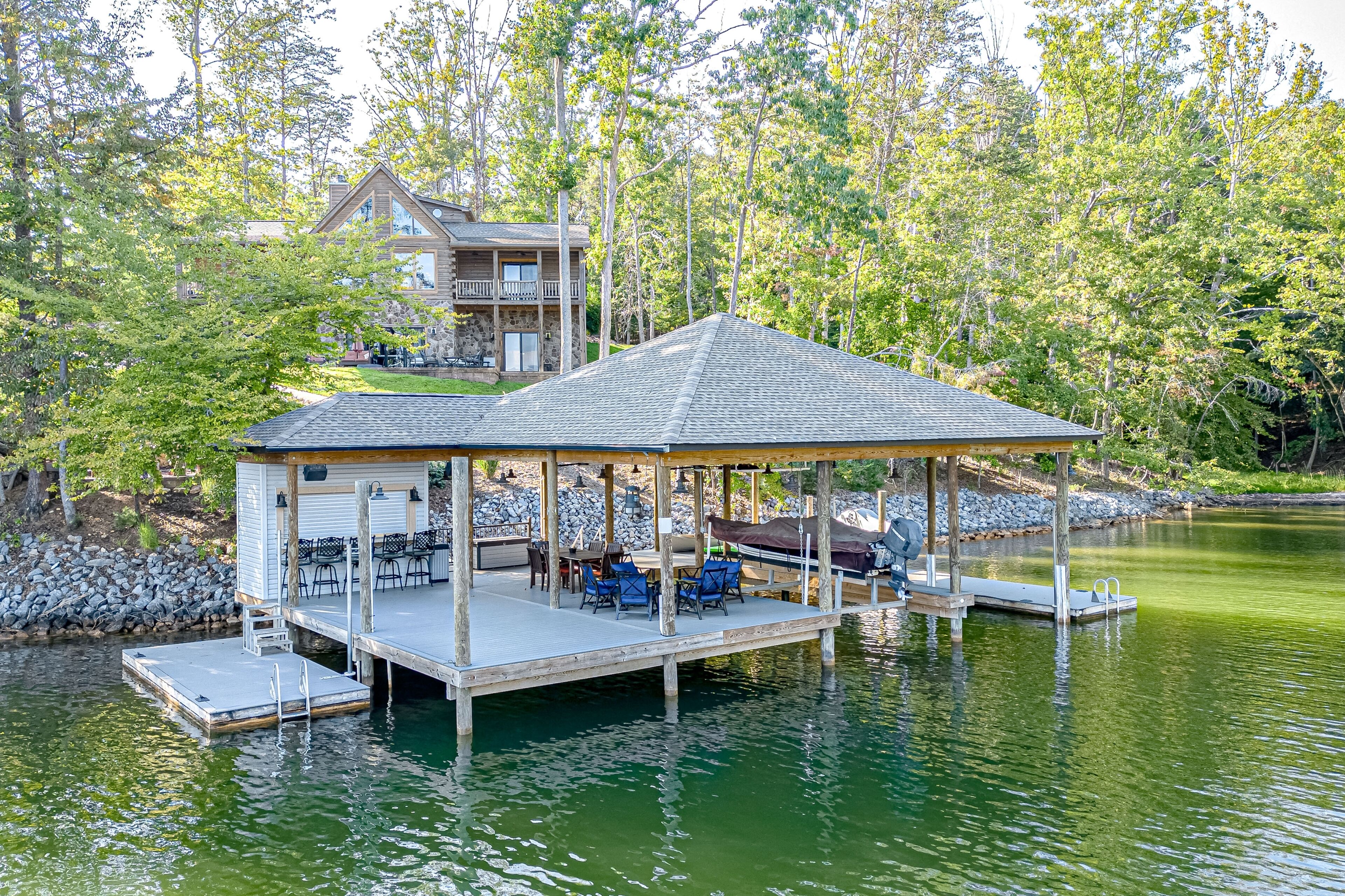 A lakeside cabin with a covered deck and outdoor seating area.