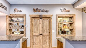 Zona de bar con puertas de madera, estantes con botellas de licor y carteles que indican 'Beer,' 'Whiskey' y 'Wine'.