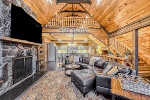 Ein Holzblockhaus-Interieur mit Kamin aus Stein, Ledersofa und Essbereich.