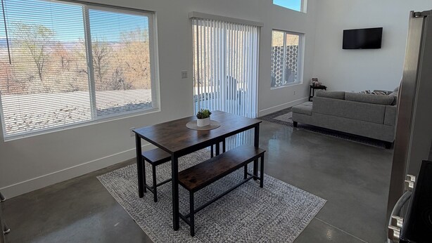 Un espacio habitable amplio con una mesa de comedor, banco y ventilador de techo.