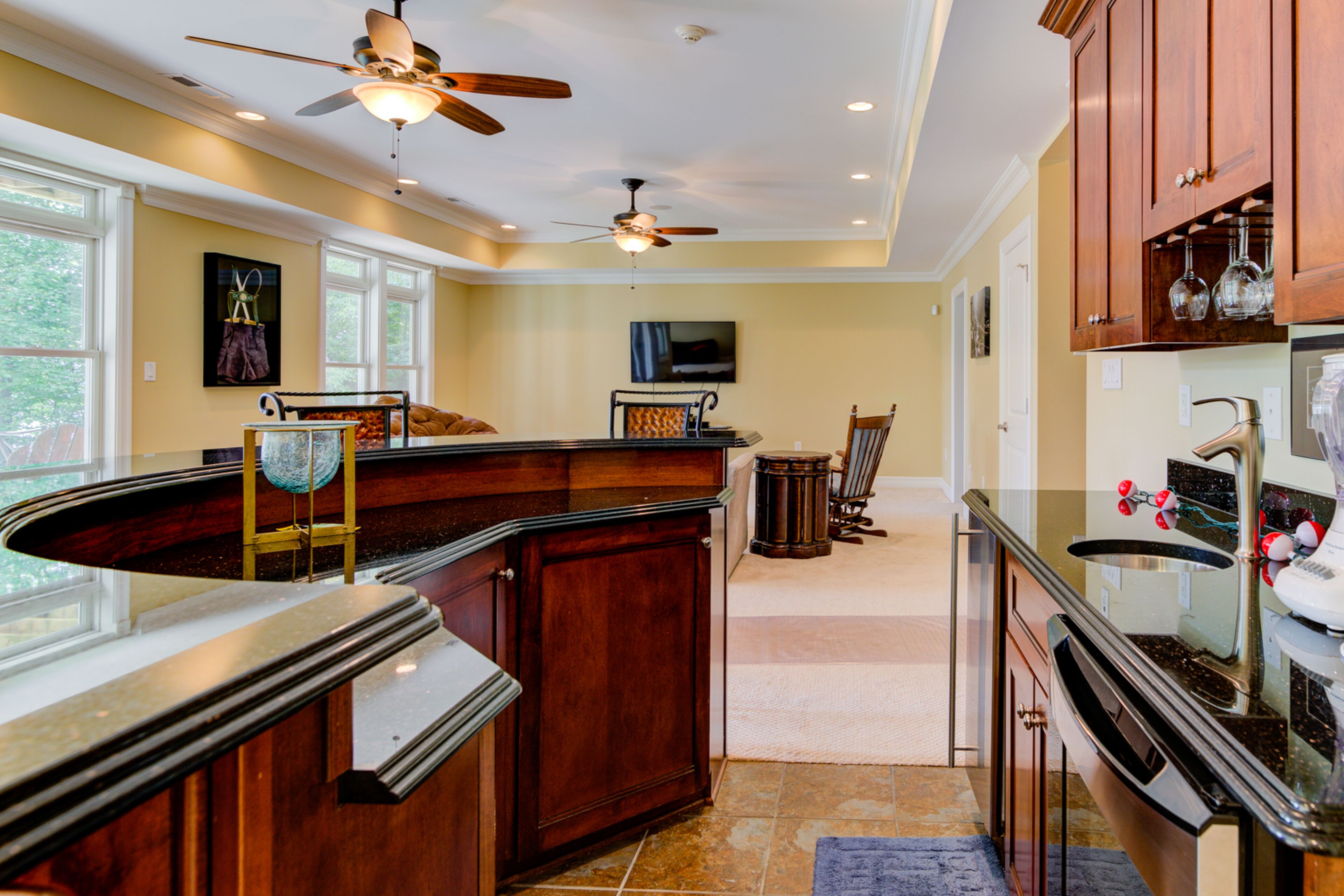 A modern kitchen with a curved island, wooden cabinets, and a ceiling fan.