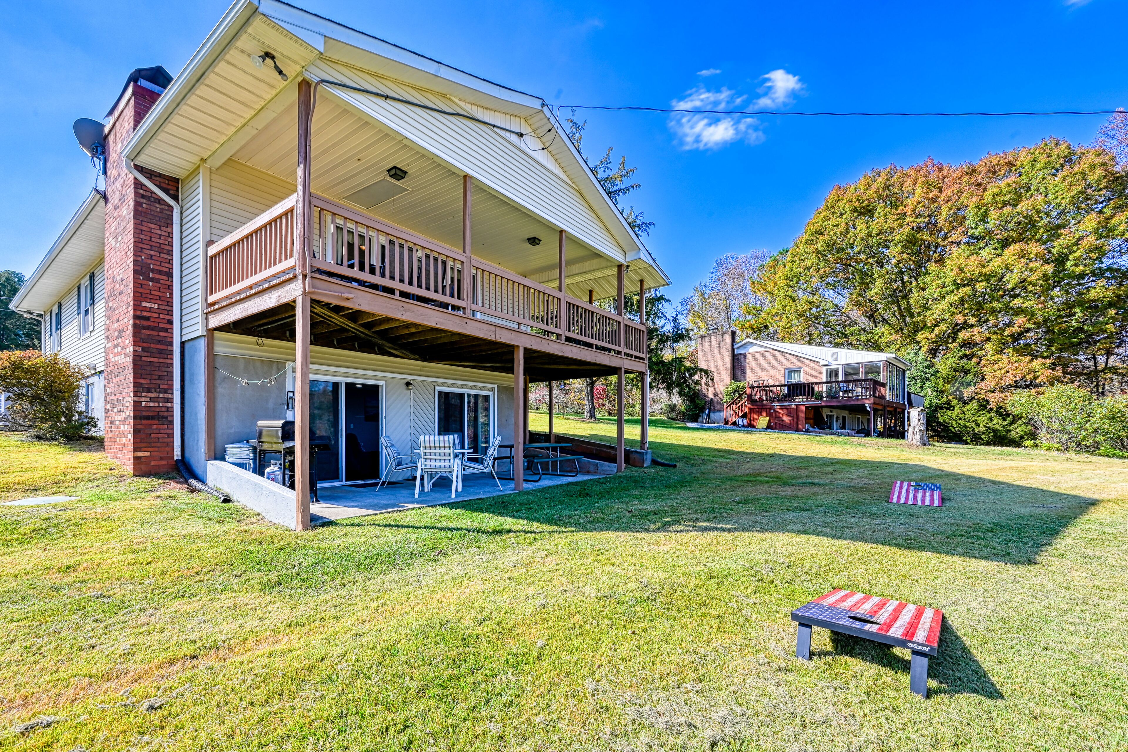 A two-story house with a covered porch, a brick chimney, and a lawn with outdoor furniture.
