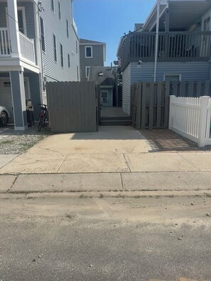 A residential area with a gated driveway leading to a house with a covered porch.